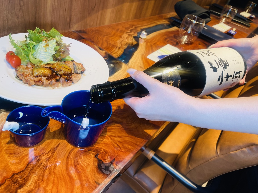 ともえの料理に合わせて日本酒を注ぐ様子